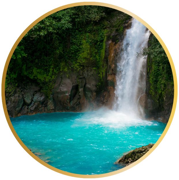 Ein Wasserfall stürzt in einen türkisblauen See, umgeben von grüner Vegetation.